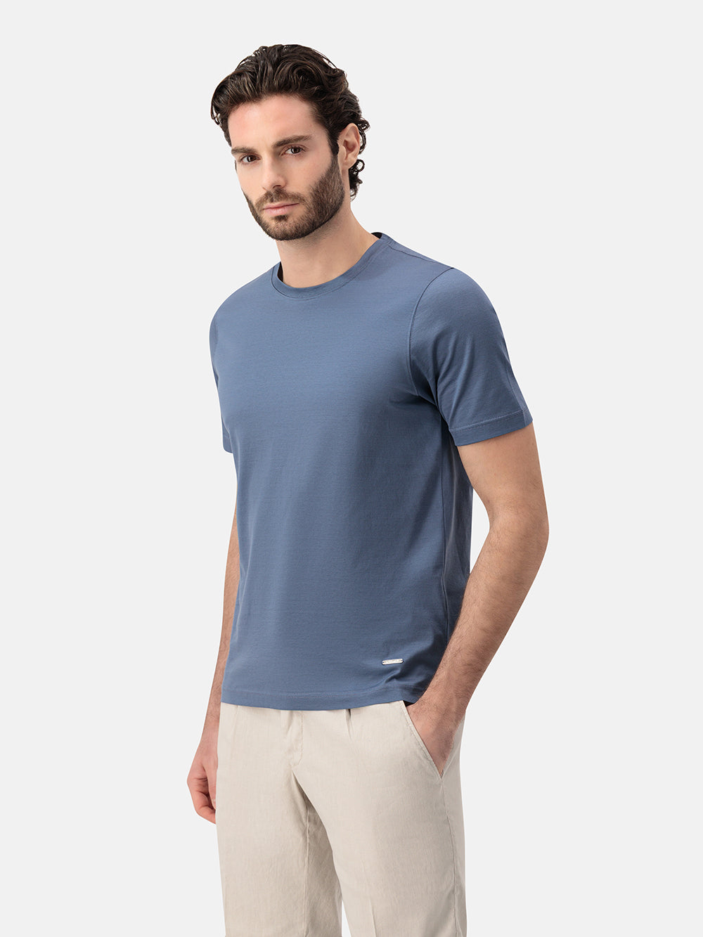 Man wearing a blue t-shirt and beige pants on a white background