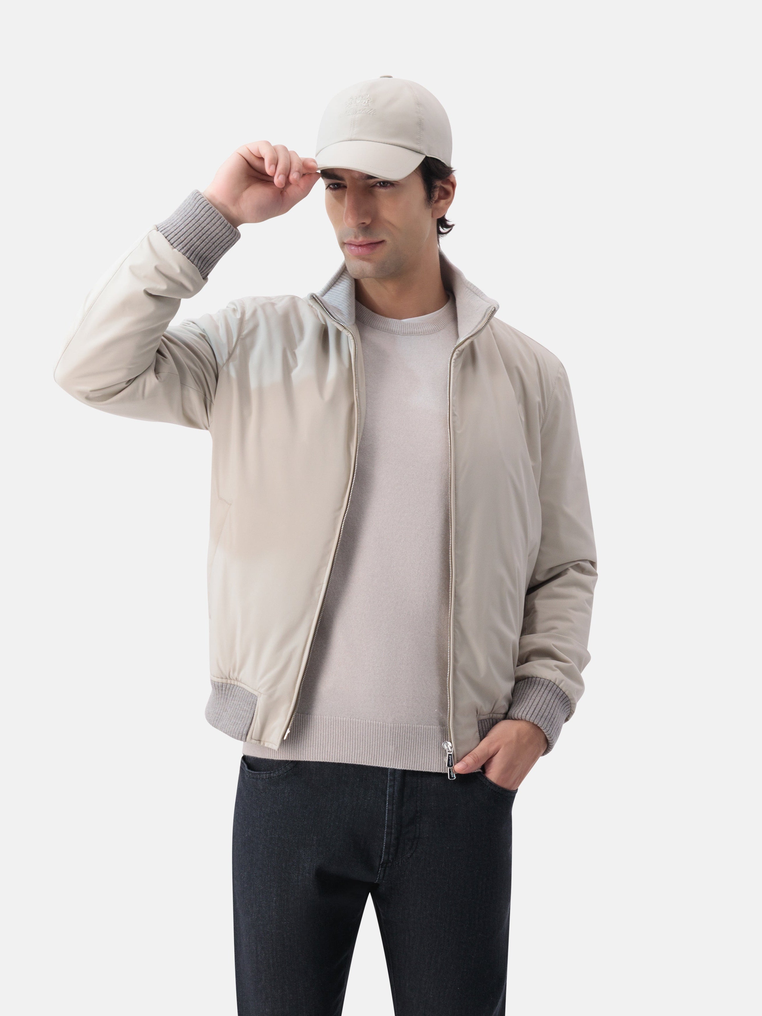 Man wearing a beige jacket, white shirt, black pants, and cap on a white background